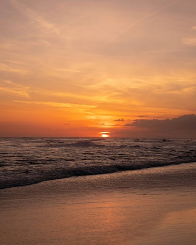 Warm orange sunset over the Gulf Coast beach with waves rolling onto the sand