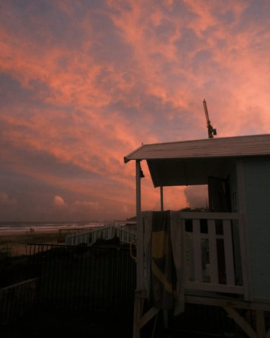 Dramatic pink and red sunset sky over a white beach hut on the Gulf Coast