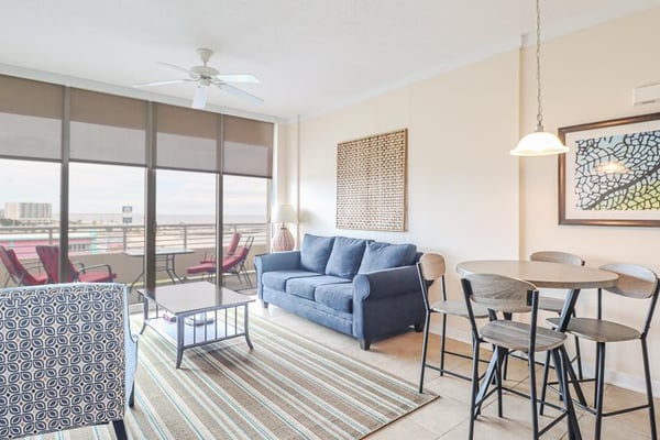 High-rise apartment living room with blue sofa, dining table, and balcony overlooking city skyline