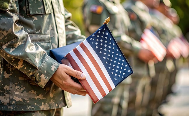 Soldiers in camouflage uniforms holding small American flags